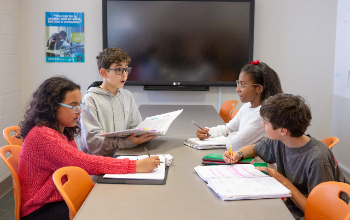 Middle school students sitting at table working on project together