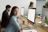 Student sitting at computer monitor smiling