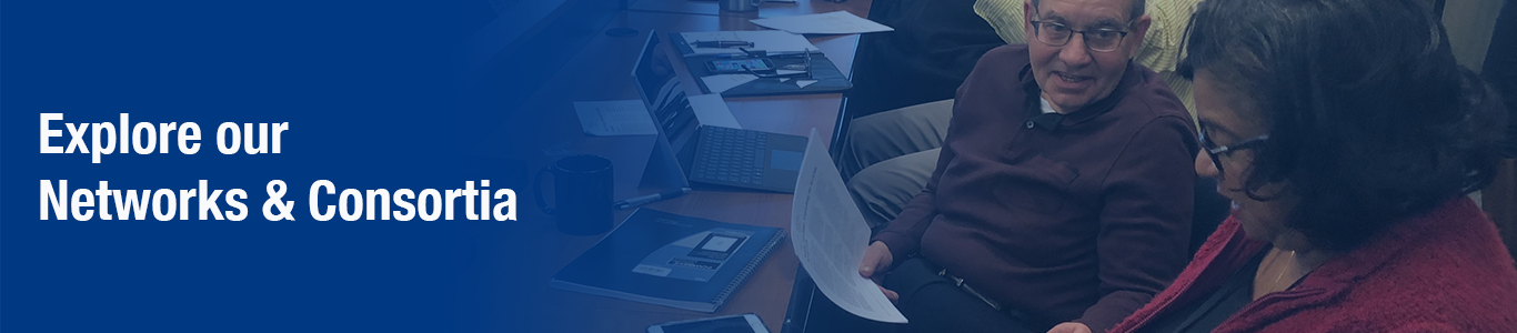 man and woman at desk looking at computer and paper smiling. blue gradient with white text. "Explore our Networks & Consortia"